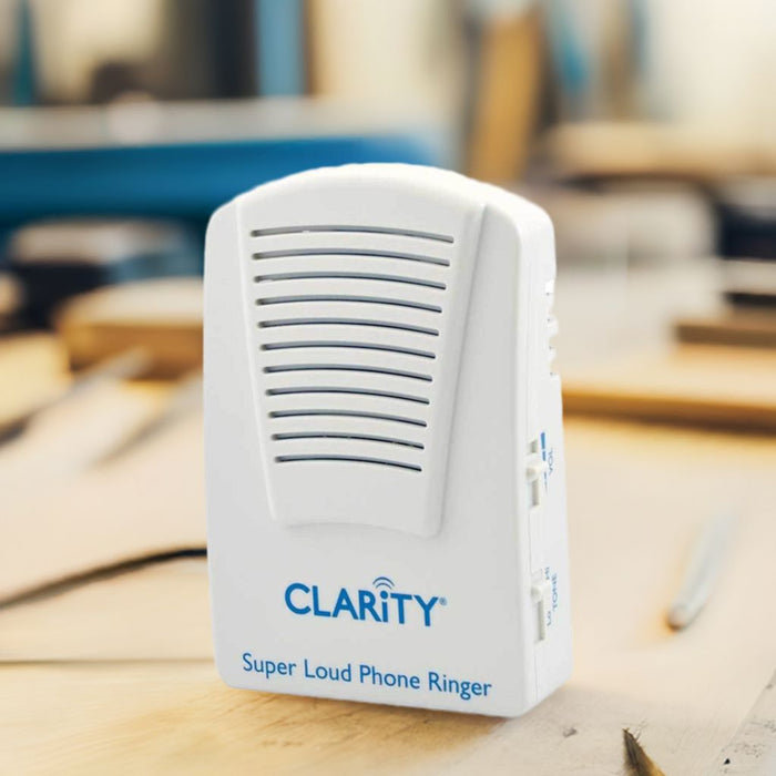 Clarity super loud phone ringer on a wooden surface with a blurred background.