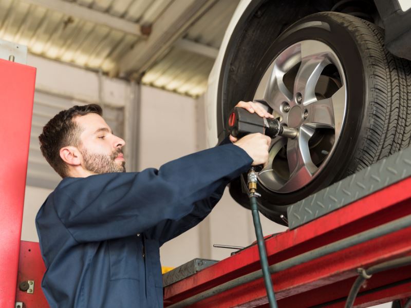 Serenity Choice Reusable Hearing Protection  for use with impact sounds such as in a tire shop.  A bearded gentleman dressed in blue coveralls is installing tires holding an impact wrench. 