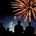 Serenity Choice Reusable Hearing Protection used during a fireworks display.  A group of people gather below a red fireworks display. 