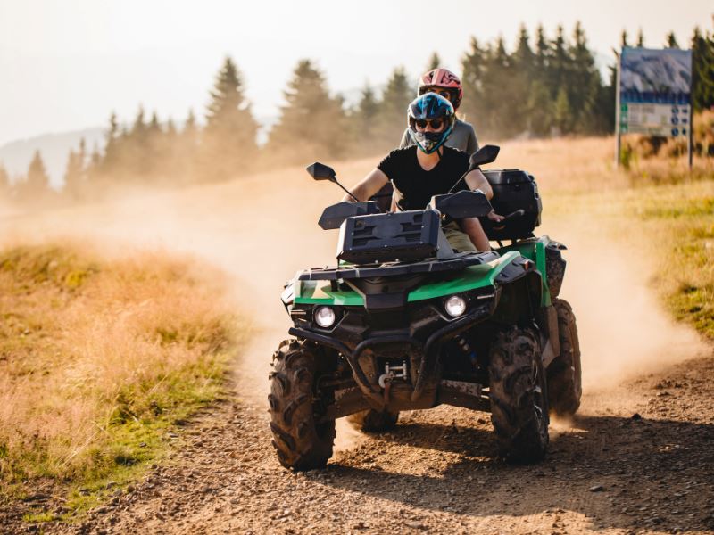 Serenity Choice Reusable Hearing Protection for MOTORSPORTS Earplugs  are used under the helmet while two people ride a quad down a dusty gravel road. 