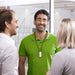 Phonak Roger Neckloop Universal Receiver 056-4005-P5111 used in the workplace.  Man in a green shirt wears the Phonak Roger Neckloop around his  neck while speaking to co-workers. 